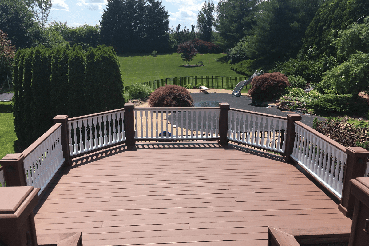 Brown wooden deck overlooking backyard pool and lawn