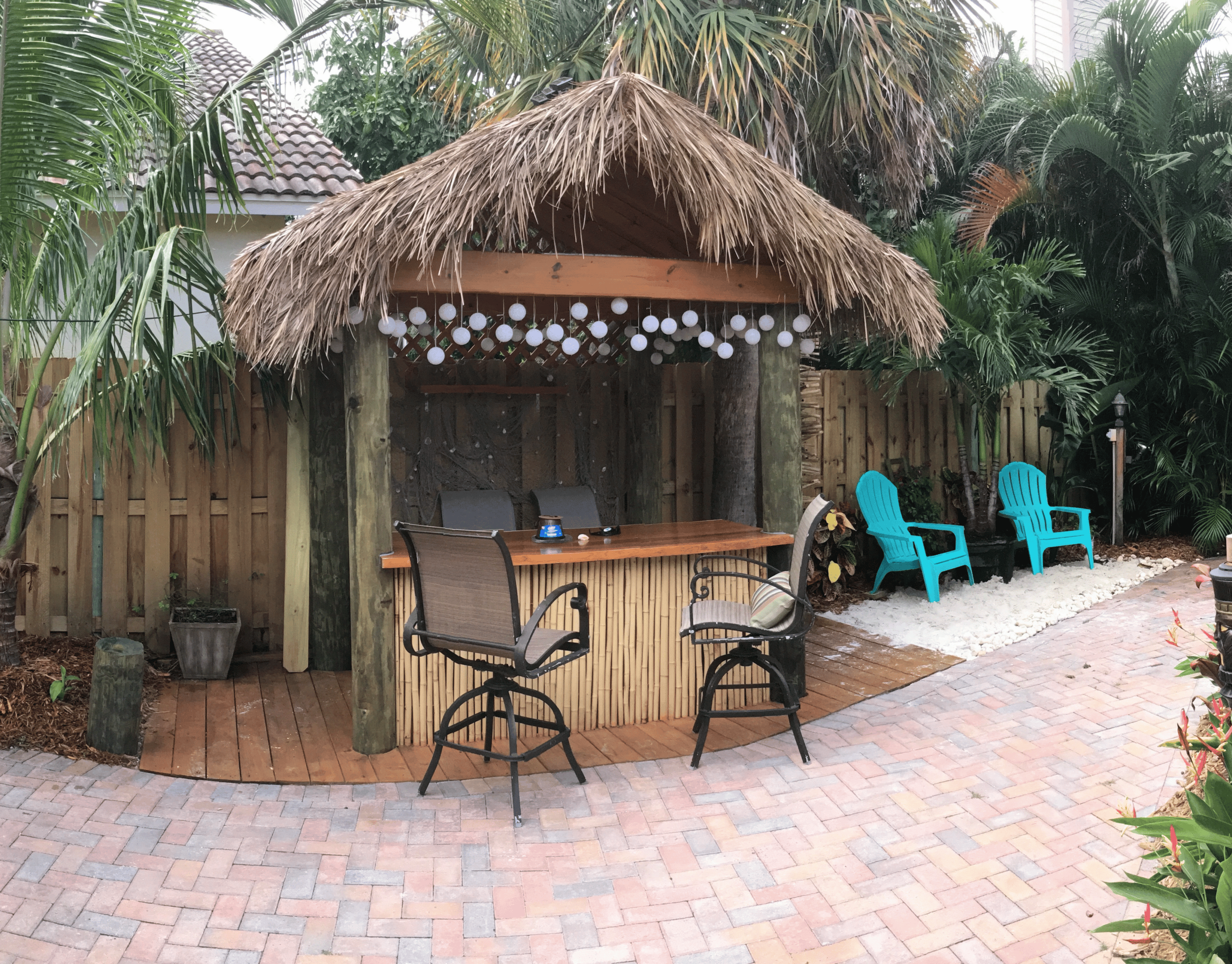 Thatched backyard tiki bar with stools