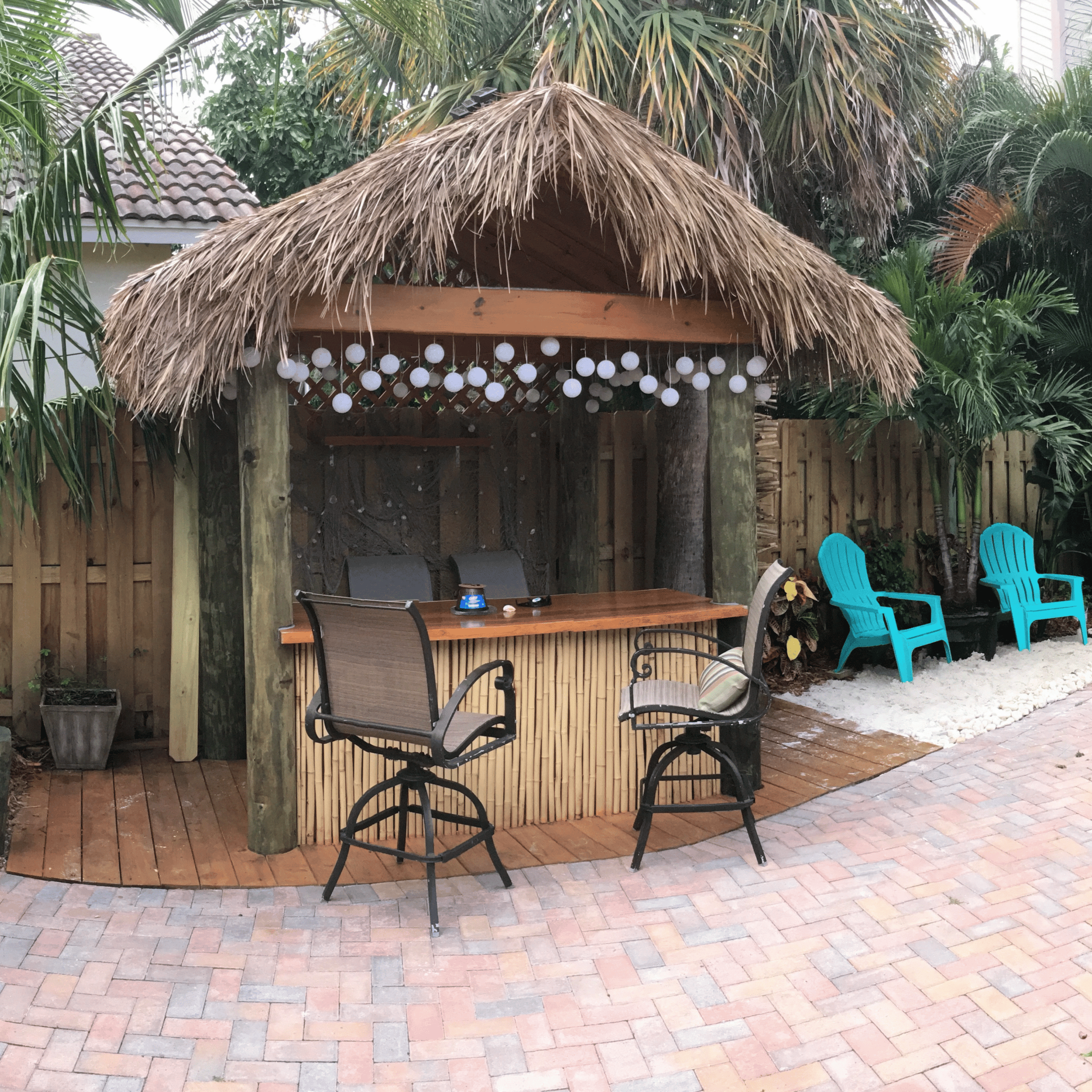 Thatched backyard tiki bar with stools