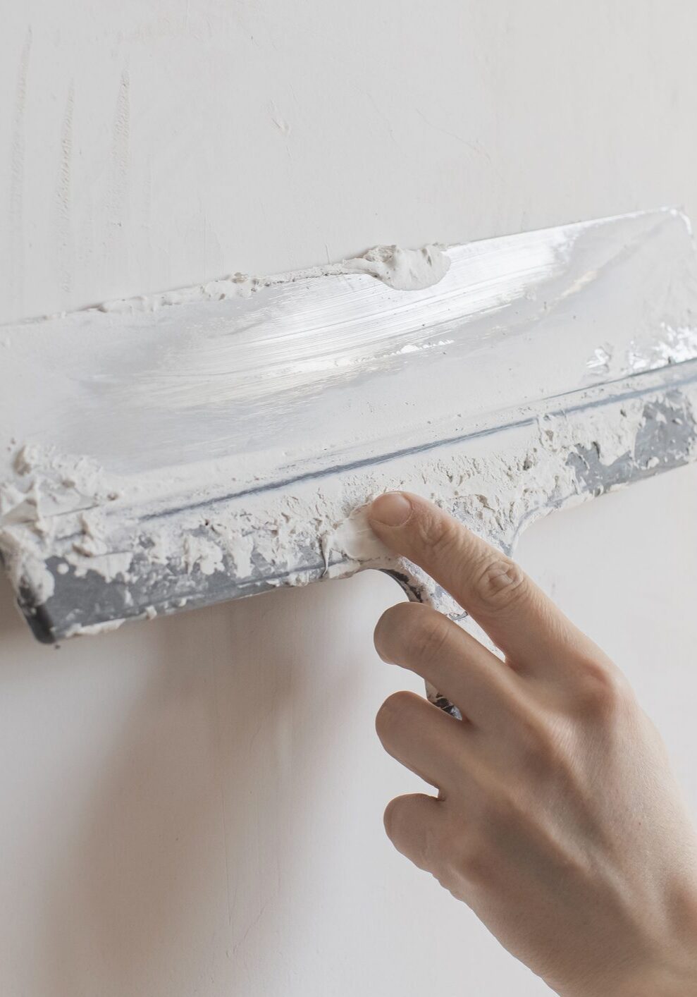 Hand smoothing white plaster with putty knife